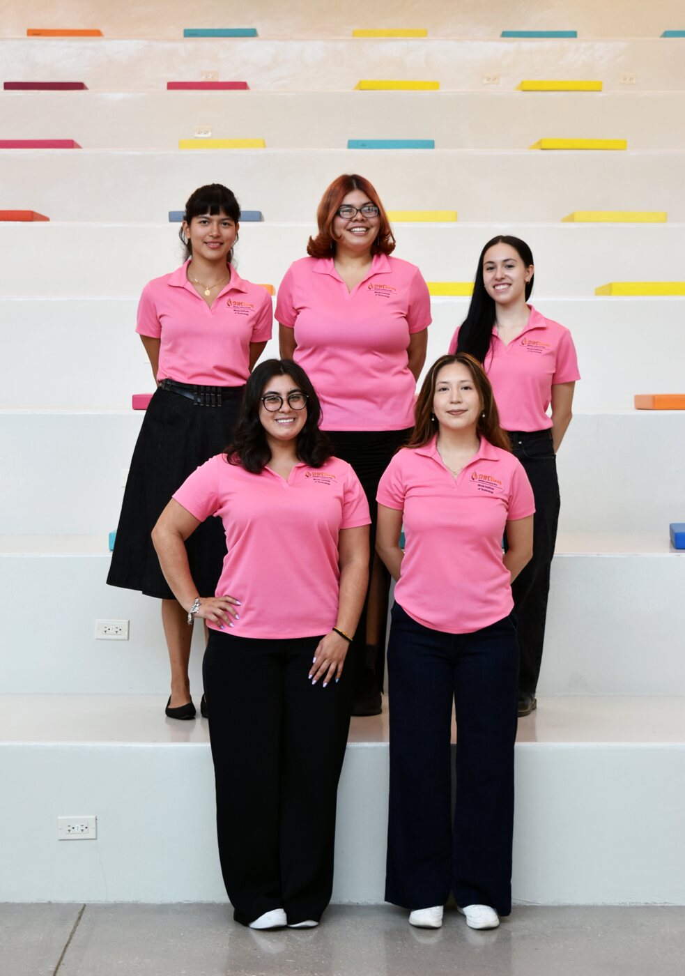 The SHPEtinas team at Illinois Tech in matching pink polos on white steps; Daniela is in the front row, on the right.