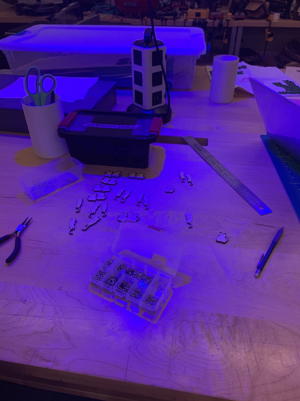 Workbench with pliers, earring hooks and laser-cut cat pieces laid out for assembly